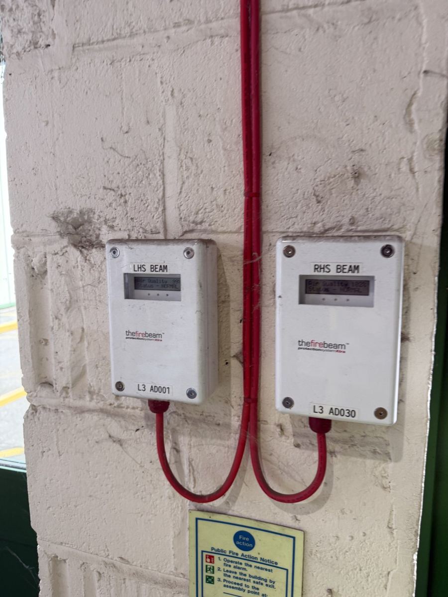 Two optical beam smoke detector controllers mounted on a warehouse column