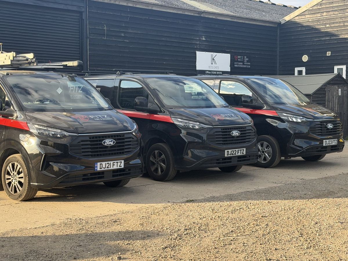 Three black FITZ FIRE & SECURITY vans with red livery parked outside the yard