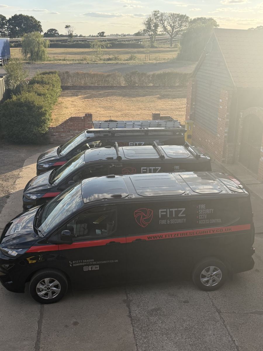 FITZ FIRE & SECURITY vans lined up in the yard in evening sun