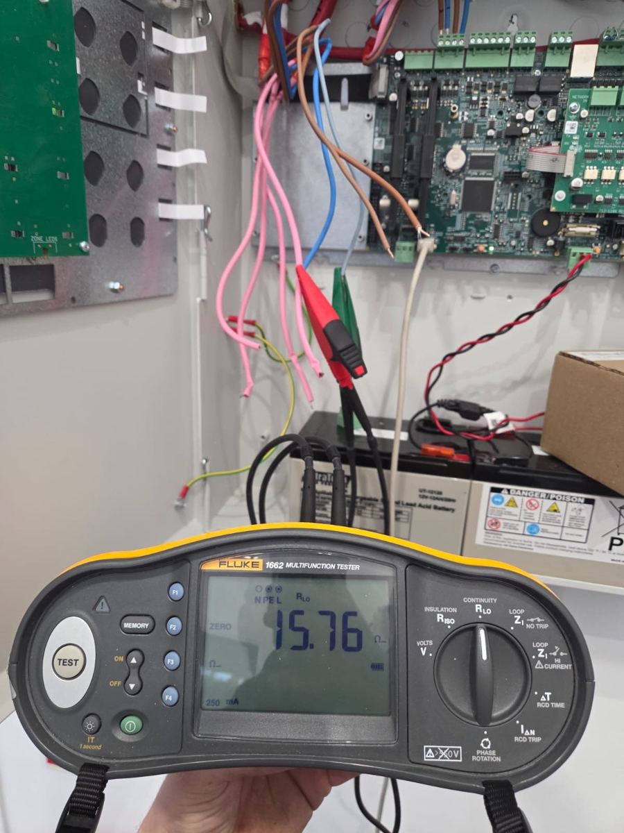 Engineer testing a fire alarm installation with a Fluke multifunction tester