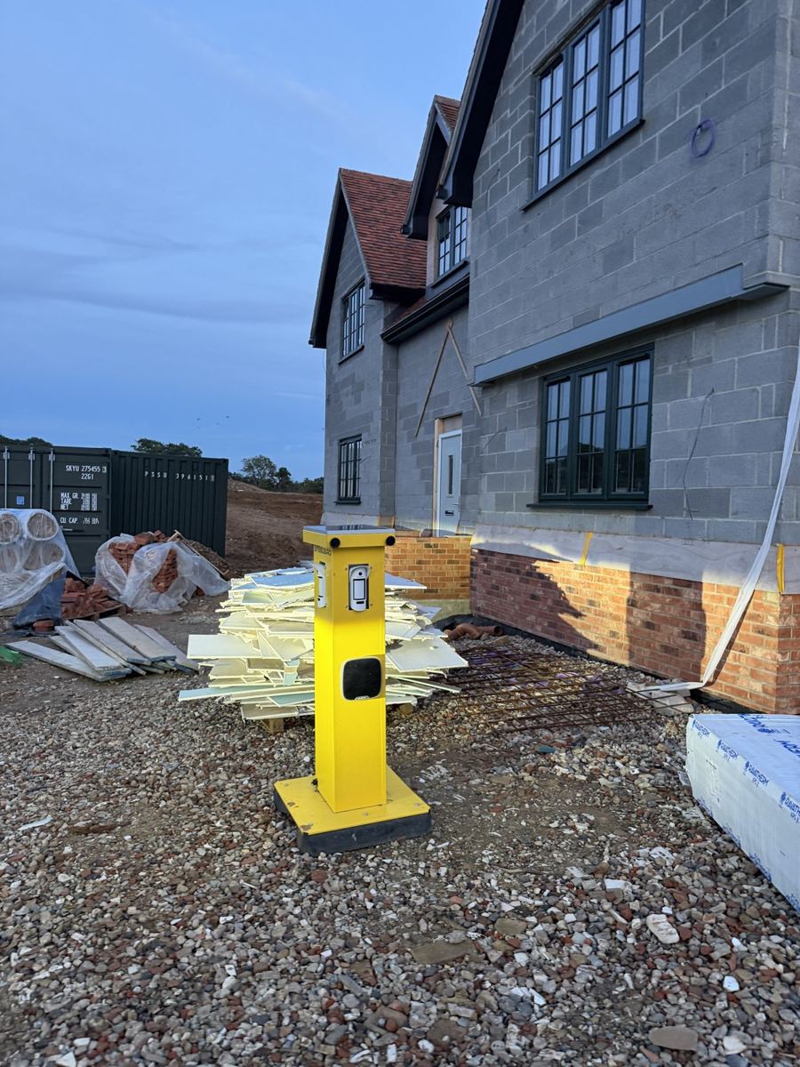 Yellow wireless site fire alarm point on a new-build housing development